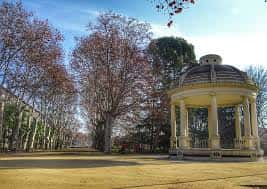 Vista amplia del gazebo en un día soleado con césped y árboles sin hojas en el parque