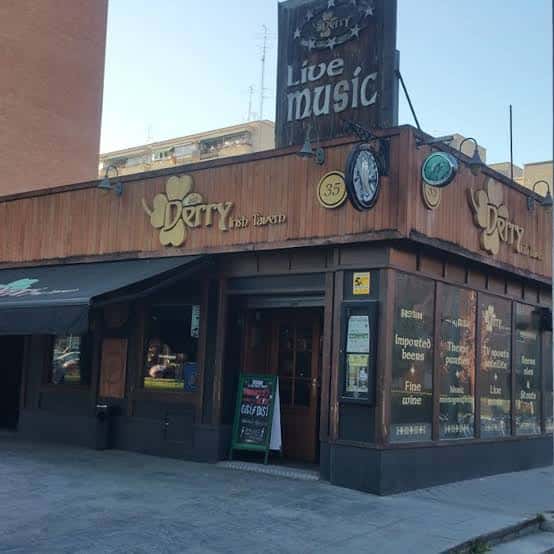 Vista diurna del exterior de Derry Irish Tavern en esquina, mostrando su fachada de madera y letreros característicos