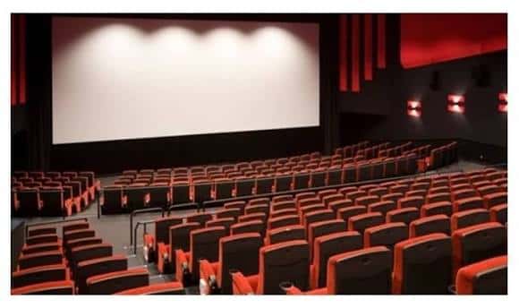 Interior de la sala de cine con butacas rojas y pantalla grande lista para proyección