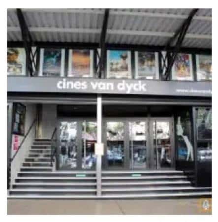 Entrada principal del cine con cartelera de películas y escaleras de acceso