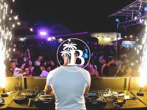 DJ en acción frente a una multitud en la terraza de Bonamara con efectos de luz