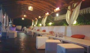 Terraza interior de Bonamara con mesas blancas, cojines naranjas y decoración elegante