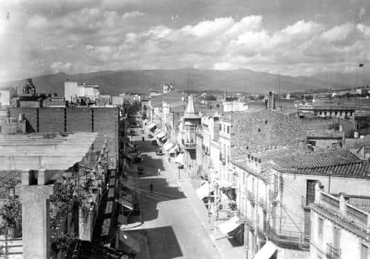 Vista panorámica del Carrer d'Anselm Clavé con montañas al fondo y tejados típicos