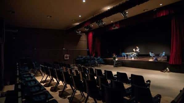 Interior del auditorio con escenario, cortinas rojas y butacas dispuestas para evento