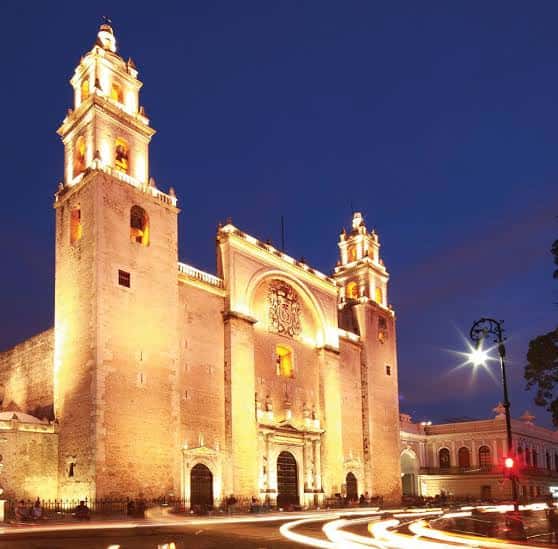 Catedral iluminada por la noche con luces de tráfico