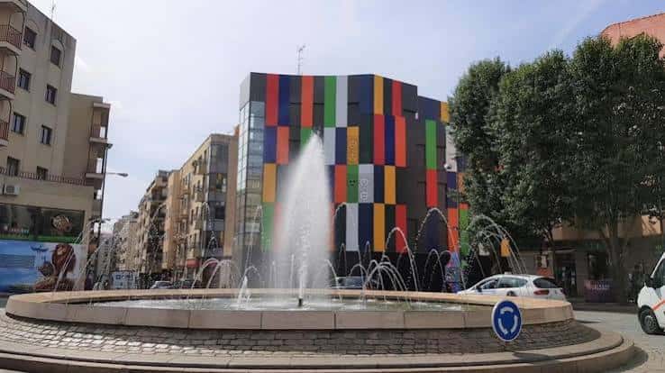 Plaza del Oeste con fuente central y edificio de fachada multicolor