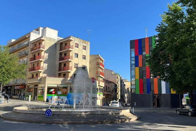 Vista amplia de la plaza con fuente y entorno urbano bajo cielo despejado