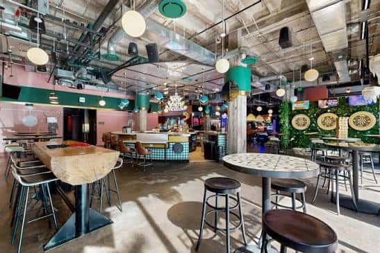 Área de bar con mesas altas y decoración industrial