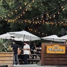 Jardín exterior de Zilker Brewing Company con luces colgantes y mesas al aire libre