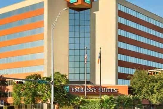Fachada frontal del Embassy Suites con letrero y banderas