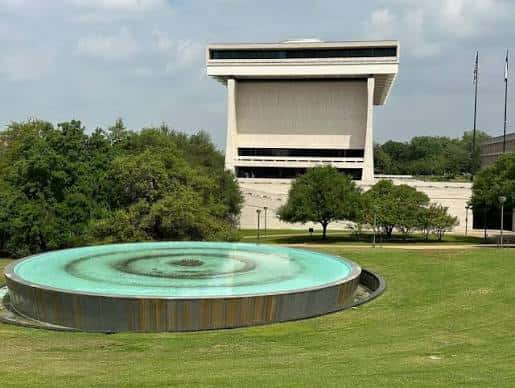 Vista del LBJ Presidential Library con fuente circular en primer plano y césped verde