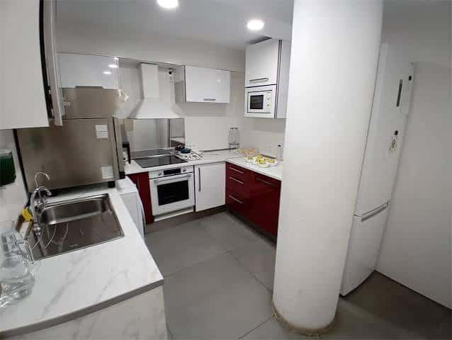 Cocina equipada con electrodomésticos y encimera blanca