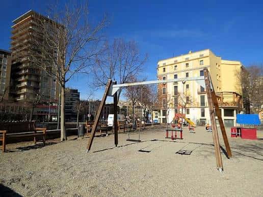 Zona de juegos infantiles en el Jardí de la Infància con columpios y arena