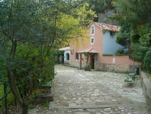 Acceso a la ermita rodeada de vegetación y camino empedrado