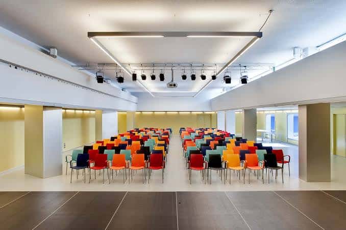 Sala de eventos con butacas de colores y escenario