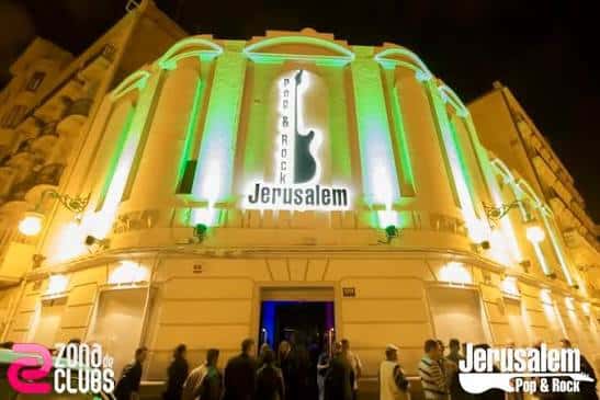 Fachada iluminada de la Sala Jerusalem con luces verdes y público en la entrada