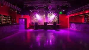 Vista del interior de la sala con luces púrpuras y barra lateral