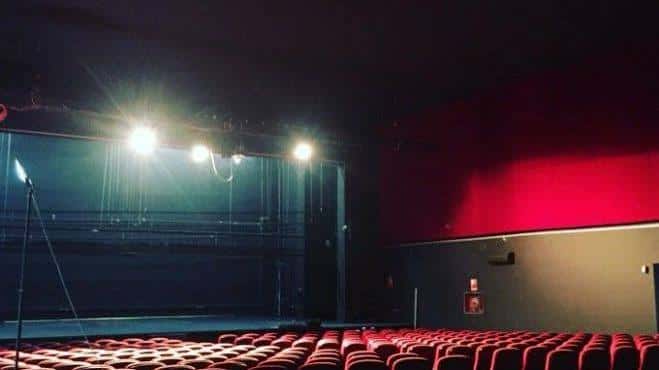 Vista del escenario del Teatro Flumen con luces de escenario y butacas rojas