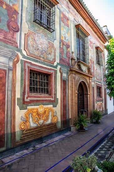 Fachada histórica del museo con decoración mural y entrada arqueada en calle empedrada