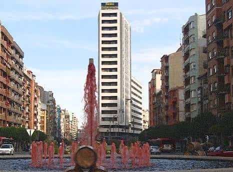 Fuente iluminada en la Gran Vía de Logroño con rascacielos al fondo