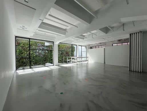 Salón de eventos espacioso con suelo de mármol y grandes ventanales a un jardín