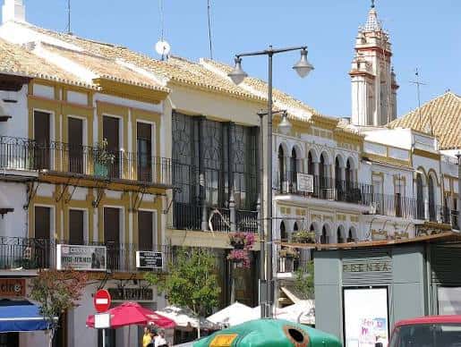 Vista de la fachada de la Plaza del Altozano con edificios históricos y la torre de la iglesia al fondo