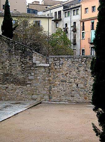 Vista de la plaza con muros de piedra y edificios históricos al fondo