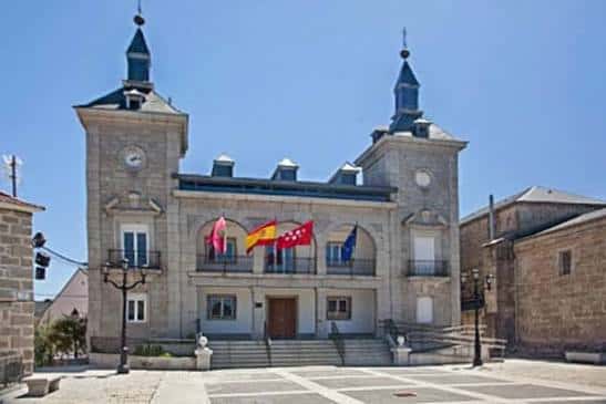 Fachada principal del Ayuntamiento de Collado Villalba con banderas y plaza frontal