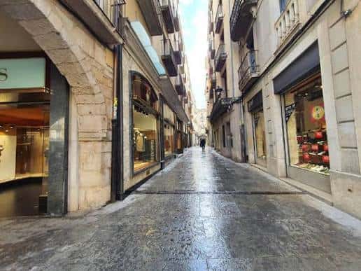 Calle empedrada del Carrer dels Abeuradors con escaparates y arquitectura tradicional