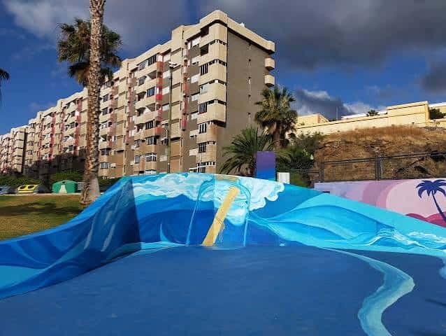 Área de skate con murales artísticos y diseño de olas pintadas en el suelo