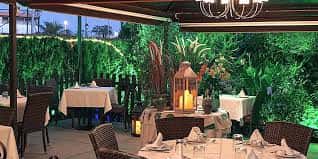 Terraza exterior de El Carnicero 1993 con mesas dispuestas para cena y decoración con velas y vegetación