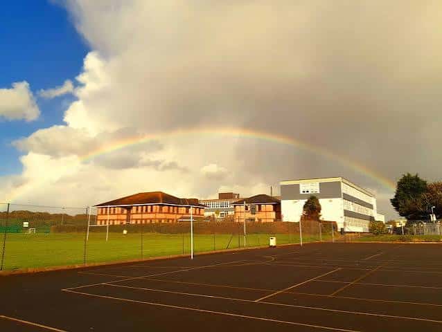 Vista exterior de Plymstock School con un arcoíris sobre los campos deportivos