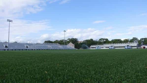 Campo de fútbol con gradas al fondo bajo cielo azul