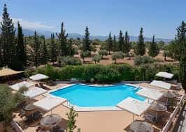 Vista panorámica de la piscina exterior rodeada de jardines y montañas