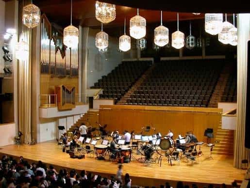 Interior del auditorio con orquesta en escena y público asistiendo
