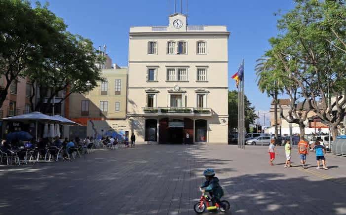 Plaza con niños jugando y gente sentada en terrazas