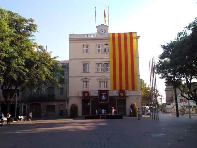 Fachada del ayuntamiento con gran bandera catalana y escenario montado