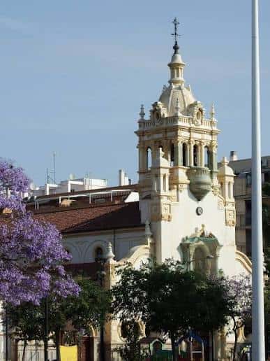 Torre campanario de la iglesia con flores de jacaranda en primer plano