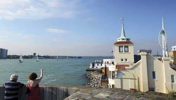 Pareja observando el puerto desde las murallas del Round Tower, con veleros y la Spinnaker Tower en el horizonte
