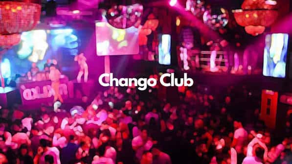 Pista de baile llena de gente bajo luces rojas y el nombre del club en pantalla