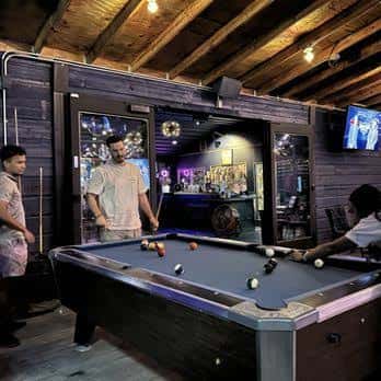 Jugadores jugando billar en el interior del establecimiento con ambiente acogedor