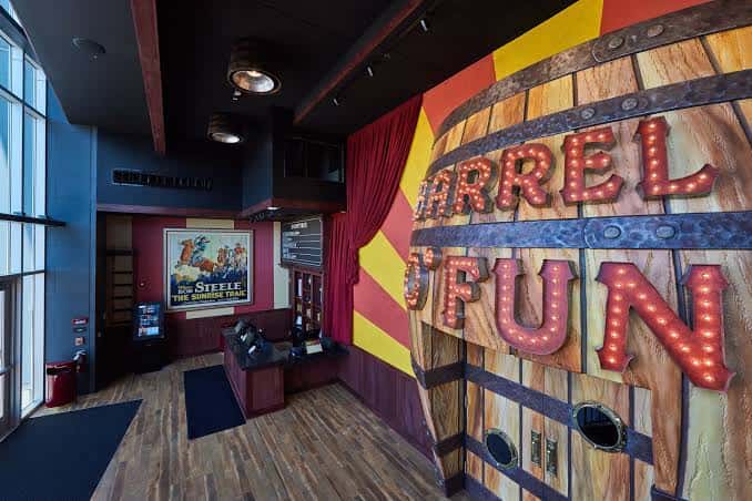Área de recepción con decoración temática de circo y letrero luminoso 'Barrel of Fun'