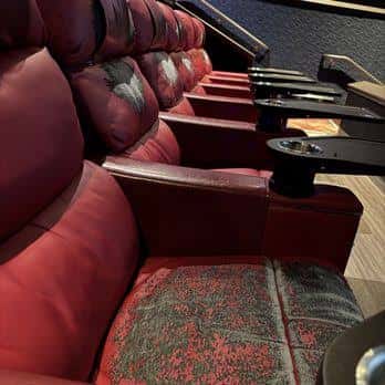 Butacas reclinables de lujo con reposabrazos y portavasos en la sala de cine