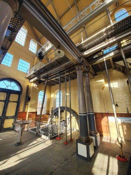 Interior de la sala de máquinas con vigas metálicas, columnas y maquinaria histórica bajo luz natural