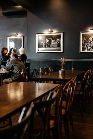 Sala de comedor con mesas de madera y cuadros en la pared