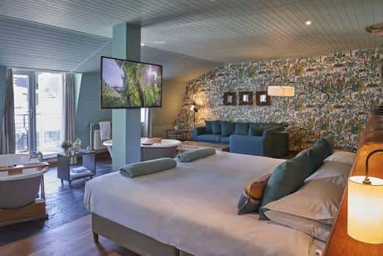 Habitación de lujo del hotel con cama grande, sofá, televisión y bañera independiente