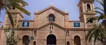 Vista frontal de la Iglesia de la Inmaculada Concepción con palmeras y banderas decorativas en los laterales
