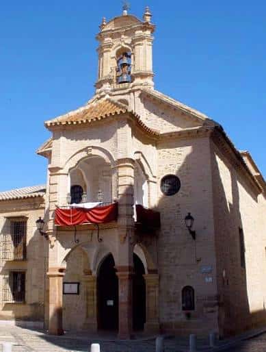Fachada principal de la Iglesia de Santiago Apóstol con balcón decorado y campanario bajo cielo azul