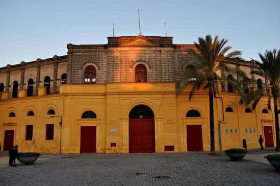 Vista exterior de la Plaza de Toros de Jerez al atardecer con fachada amarilla y arcos