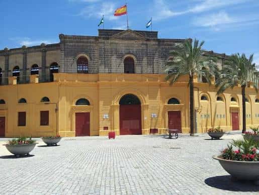Plaza de Toros de Jerez con banderas ondeando y macetas decorativas en primer plano